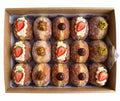 A box of 15 assorted fried dough pastries topped with cream, sliced strawberries, chocolate pieces, and nuts, arranged in a brown cardboard tray. pre order at Blue Moon Bakehouse, bakery on 70 Riccarton Road, Christchurch
