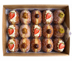 A box of 15 assorted fried dough pastries topped with cream, sliced strawberries, chocolate pieces, and nuts, arranged in a brown cardboard tray. pre order at Blue Moon Bakehouse, bakery on 70 Riccarton Road, Christchurch