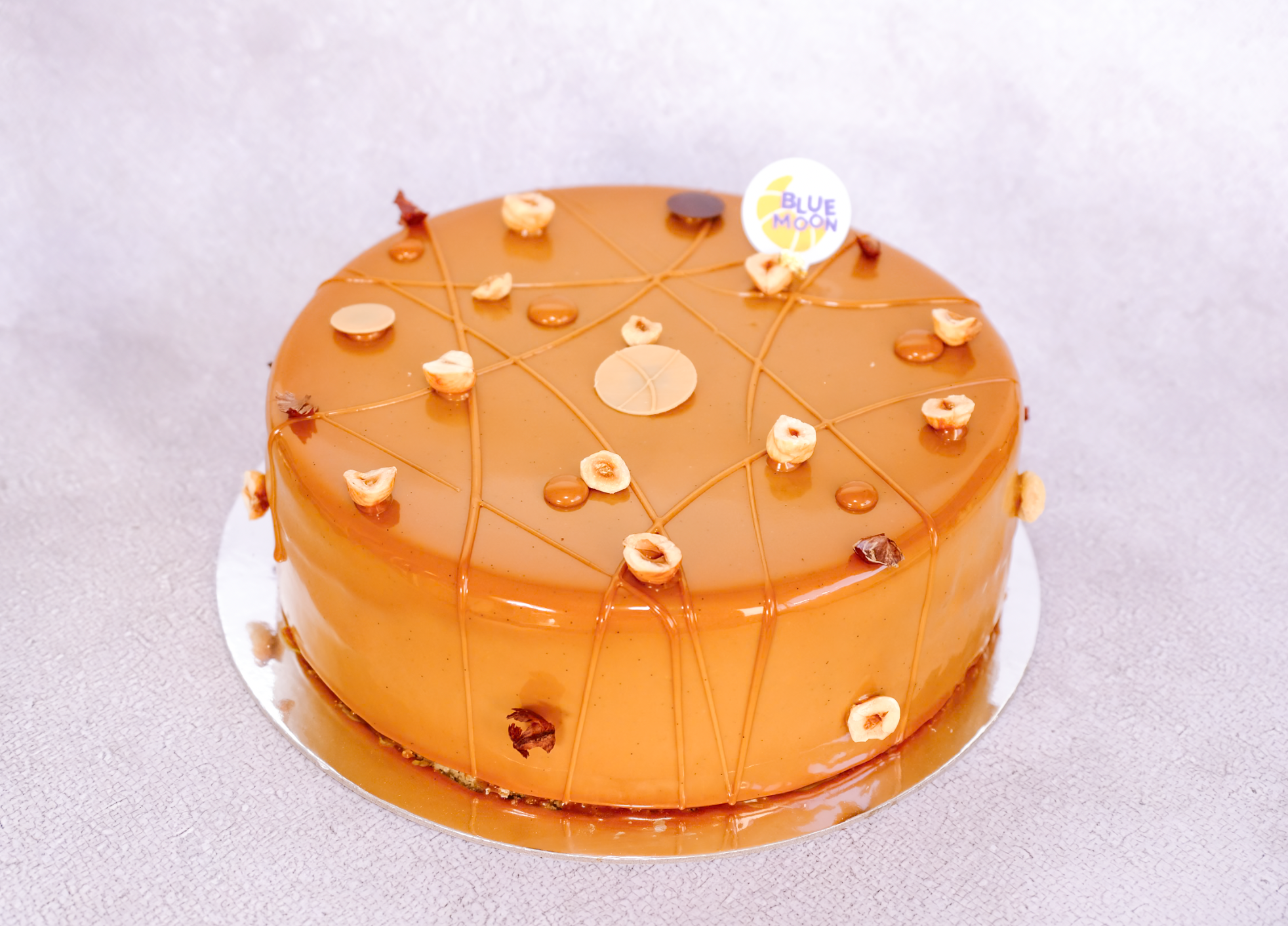 Four-layer hazelnut cake: milk choc mousse, hazelnut sponge, crispy praline & salted caramel glaze. 8" cake, 48hr pre-order. Christchurch.