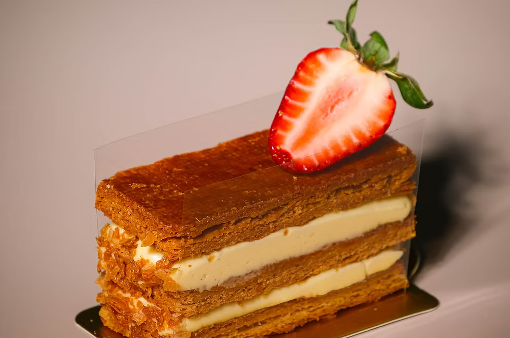 Layered cake with a strawberry on top against a neutral background