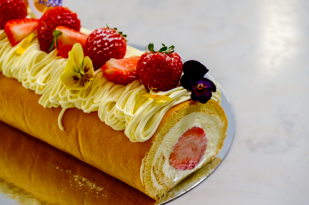 Strawberry cake roll with cream and fresh strawberries on a white background